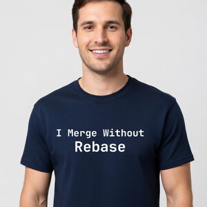 May include: Navy blue t-shirt with the white text "I Merge Without Rebase". The shirt is a crew neck style and is being worn by a person.