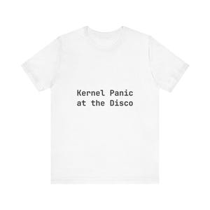 May include: A white t-shirt featuring the black text "Kernel Panic at the Disco". This casual top is suitable for everyday wear and is a simple, clean design.