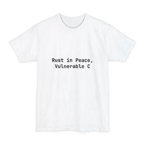 Peut inclure: T-shirt blanc avec l'inscription noire "Rust in Peace, Vulnerable C". Le t-shirt a un col rond et des manches courtes. Le texte est centré sur le devant du vêtement.