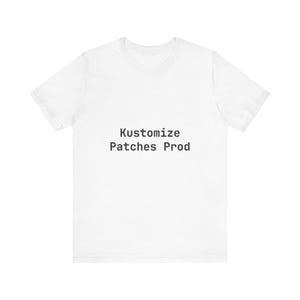 May include: A white t-shirt with the text "Kustomize Patches Prod" printed in black. The shirt is a basic crew neck style, suitable for casual wear. The text is centered on the front of the shirt.
