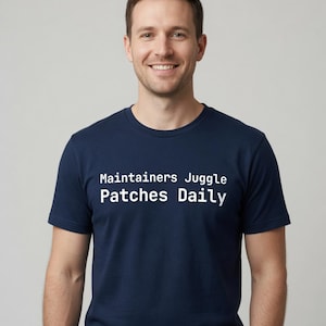 May include: A navy blue short-sleeved t-shirt featuring the white text "Maintainers Juggle Patches Daily" printed across the chest. The garment has a classic crew neckline and a standard fit, providing a clean and simple look for everyday wear.