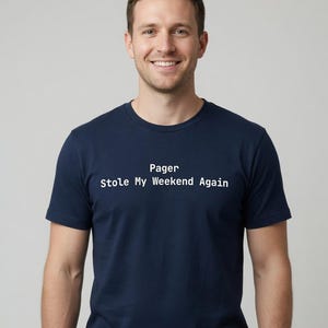 May include: A navy blue short-sleeved crew neck t-shirt featuring the white text Pager Stole My Weekend Again printed across the chest. The garment is made of a solid-colored fabric and has a standard fit with a straight hemline and short sleeves.