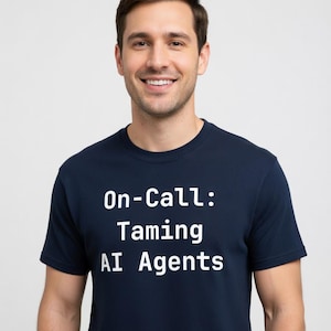 May include: A navy blue t-shirt with the text "On-Call: Taming AI Agents" in white. The shirt is a crew neck style and is being worn by a person.