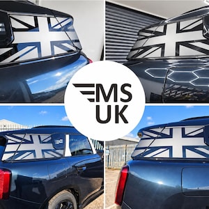 Può includere: Un veicolo di colore scuro con un adesivo della bandiera Union Jack in bianco e nero applicato sul finestrino laterale posteriore. La decalcomania mostra l'iconico motivo della bandiera britannica in stile monocromatico sul vetro.