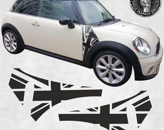 May include: A white Mini Cooper with black Union Jack decals on the side panels. The decals are in the shape of a flag and have a black and white design.