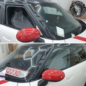 Op de afbeelding: Een witte Mini Cooper met zwarte raambekleding en een zwarte en rode streep aan de zijkant. De auto heeft een rode zijspiegel en een kentekenplaat met de tekst "G2230".