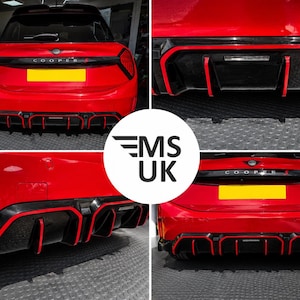 Può includere: Un paraurti posteriore rosso per Mini Cooper S con diffusore nero e finiture rosso brillante. Il veicolo presenta una modanatura nera sul bagagliaio con la scritta COOPER S e una targa gialla. Il design include alette verticali sul diffusore.