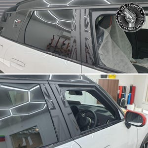 May include: A white car with black window trim and a Union Jack design on the window trim. The car is in a garage and the windows are reflecting the lights of the garage.