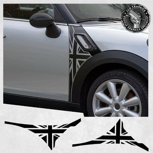 Pode incluir: Um Mini Cooper prateado com detalhes pretos e um gráfico Union Jack no lado. O carro está estacionado em uma superfície branca. O gráfico também está disponível como adesivo separado.