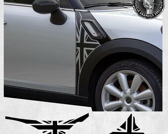 May include: A silver Mini Cooper with black trim and a Union Jack graphic on the side. The car is parked on a white surface. The graphic is also available as a separate sticker.