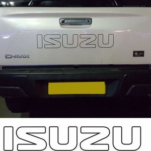 May include: A white pickup truck with the word "ISUZU" in large, bold letters on the tailgate. The truck has a black bumper and a yellow license plate.