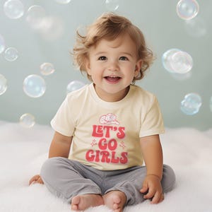 a little girl sitting on a bed with bubbles in the air