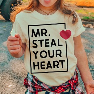 a little girl wearing a t - shirt that says mr steal your heart