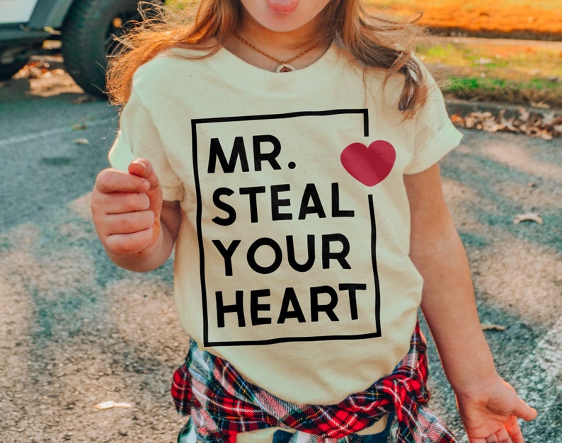 a little girl wearing a t - shirt that says mr steal your heart