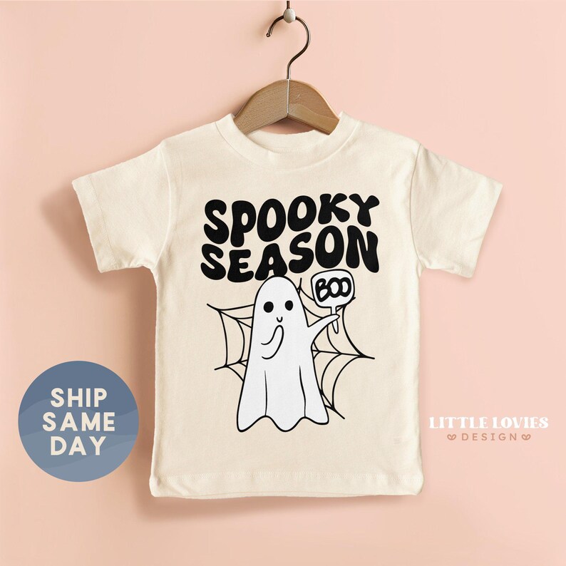 A white t-shirt with a graphic design featuring a ghost character and the text "SPOKEY SEASON BOO" printed on it.