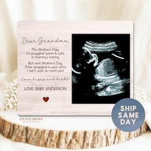 May include: A wooden picture frame with a sonogram image and text. The text reads "Dear Grandma, This Mother's Day, I'm snuggled warm & safe in mommy's tummy...Love, Baby Anderson." A heart graphic is at the bottom.
