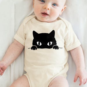a baby wearing a bodysuit with a black cat on it
