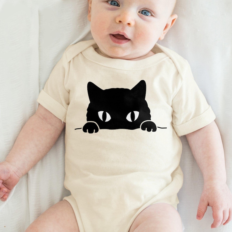 a baby wearing a bodysuit with a black cat on it