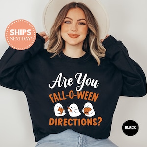 May include: Black sweatshirt with the text "Are You Fall-O-Ween Directions?" in white and orange. The design includes three cartoon ghosts holding a book, a pencil, and a pumpkin. A round sticker on the left says "SHIPS NEXT DAY".