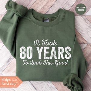 May include: A green sweatshirt with the text "It Took 80 Years To Look This Good" in white.