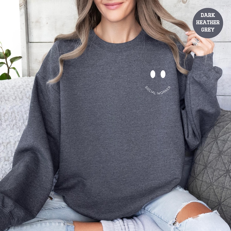 a woman sitting on a couch wearing a dark sweatshirt with a smiley face drawn on