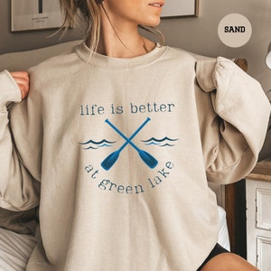 a woman wearing a sweatshirt that says life is better at green lake