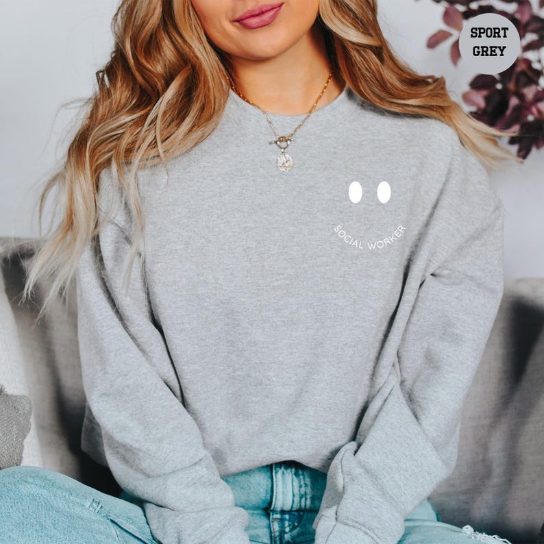a woman sitting on a couch wearing a grey sweatshirt
