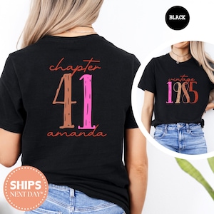 May include: Black t-shirt with the text "chapter 41 amanda" in a mix of colors. The number 41 is in brown and pink. A smaller image shows a black t-shirt with "vintage 1985" in similar colors. The word "BLACK" is in a black circle.