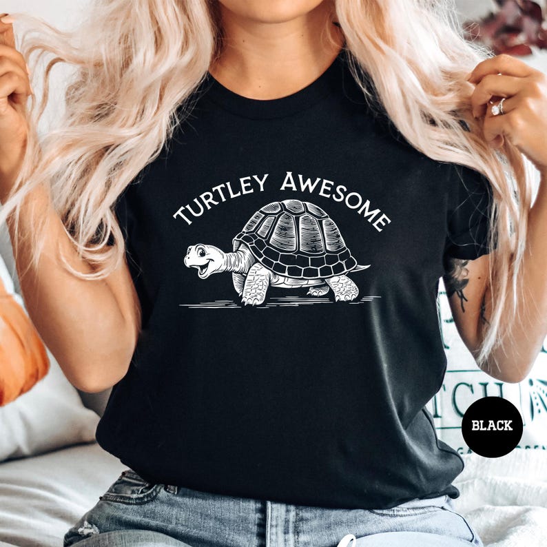 A woman wearing a black t-shirt with a graphic of a turtle and the text "TURTLEY AWESOME" printed on it.