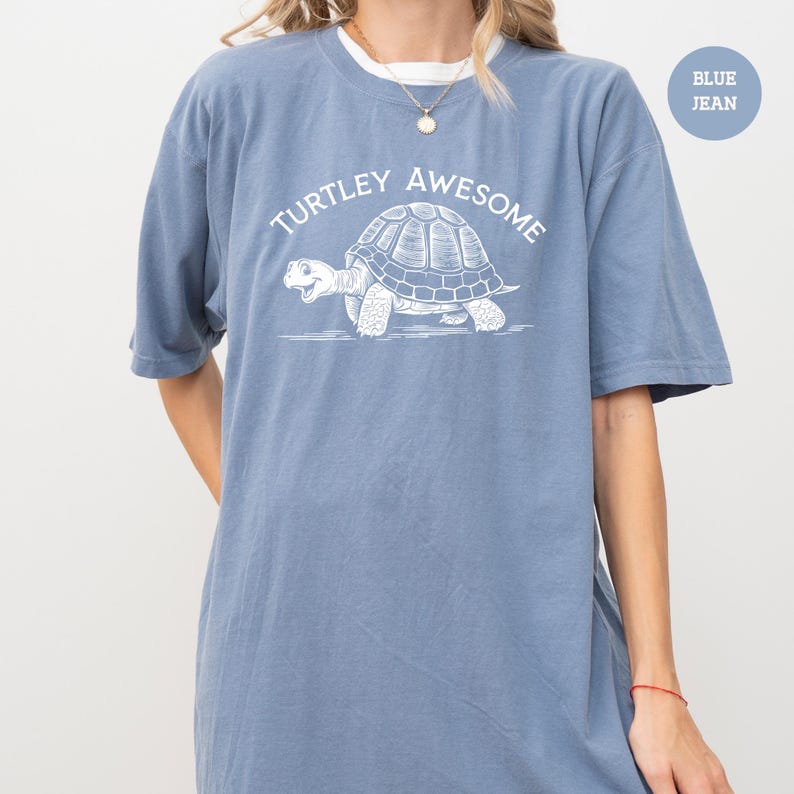 A person wearing a blue t-shirt with a graphic of a turtle and the text "TURTLEY AWESOME" printed on it.