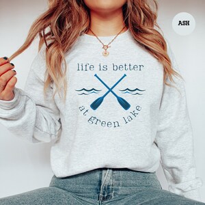 a woman wearing a sweatshirt that says life is better at green lake