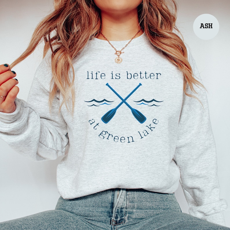 a woman wearing a sweatshirt that says life is better at green lake