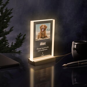 May include: A white illuminated acrylic photo frame with a picture of a golden dog. The frame has the text "Alex", "Always by your side now and forever", and "2022" engraved on it.