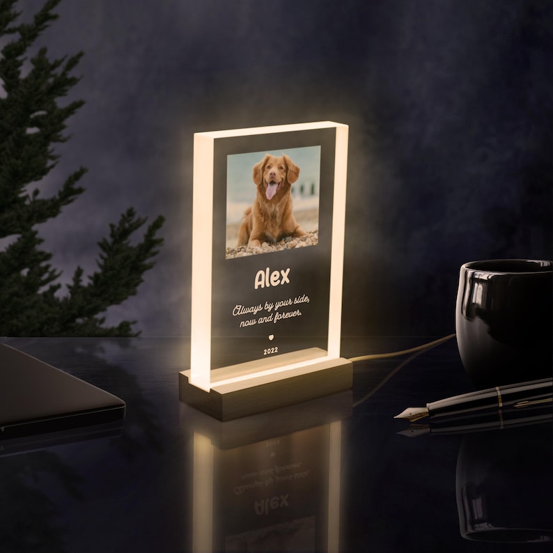 May include: A white illuminated acrylic photo frame with a picture of a golden dog. The frame has the text "Alex", "Always by your side now and forever", and "2022" engraved on it.