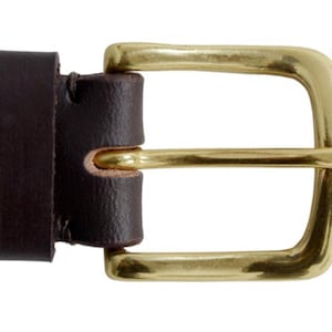 May include: A brown leather belt with a brass buckle. The buckle is a simple, rectangular design with rounded edges.