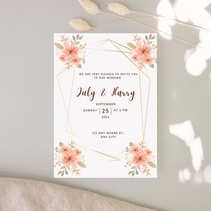 Peut inclure: Invitation de mariage avec un cadre géométrique doré et des accents floraux pêche. Le texte indique "Nous sommes très heureux de vous inviter à notre mariage. July & Harry. Septembre 25 à 17h00 2022. 123 Any Where St., Any City."