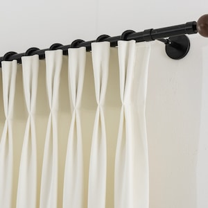 May include: Black curtain rod with wooden finials and white curtains hanging from it.