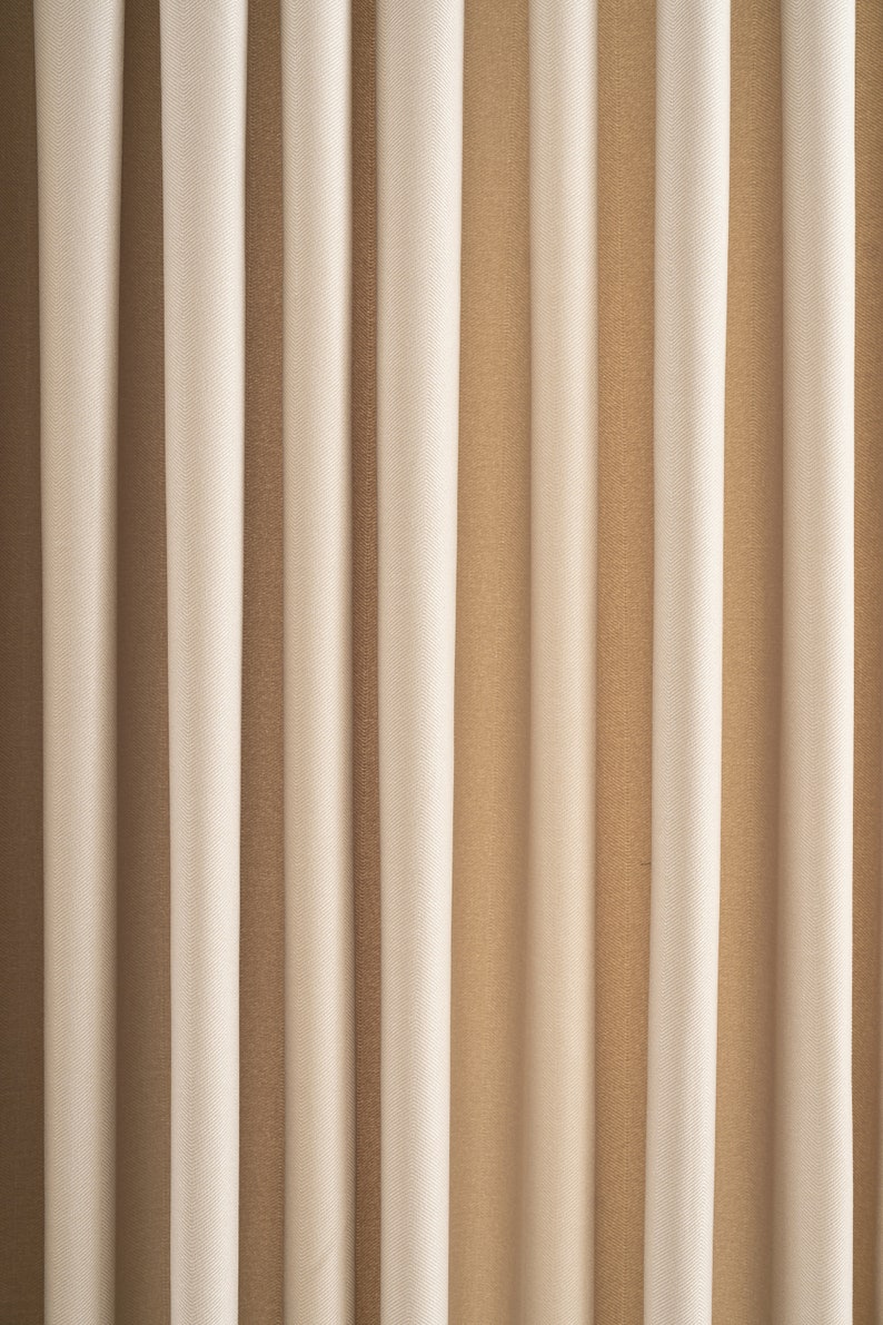 May include: A close-up of a set of beige and brown curtains with vertical stripes. The curtains are made of a soft, textured fabric.