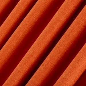 May include: Close-up of a textured, orange fabric with diagonal folds. The fabric has a woven appearance, and the color is a warm, earthy tone. The folds create shadows and highlights, adding depth to the image. The fabric appears to be a medium weight material.