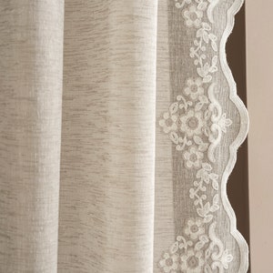Puede incluir: Una cortina blanca de gasa con un borde festoneado y un delicado diseño de bordado floral.