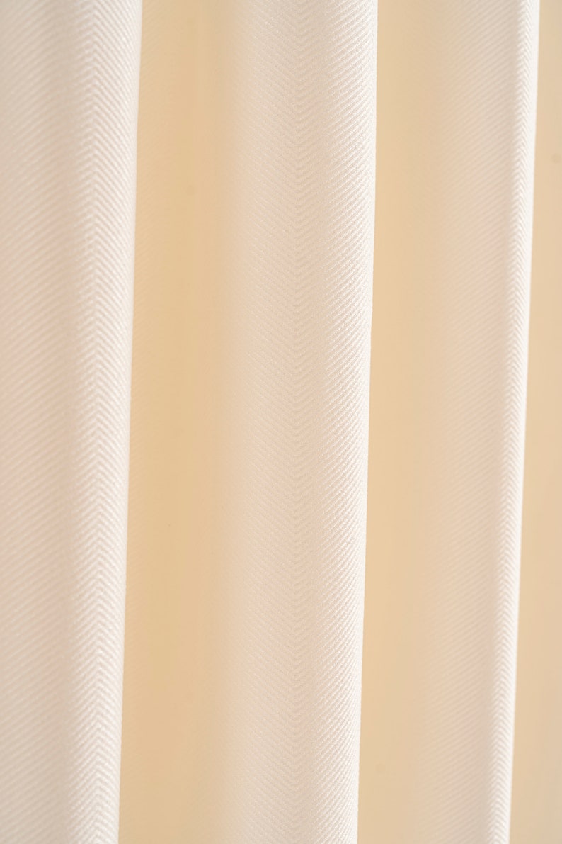 May include: Close-up of a white fabric with a herringbone pattern. The fabric has a soft, smooth texture.