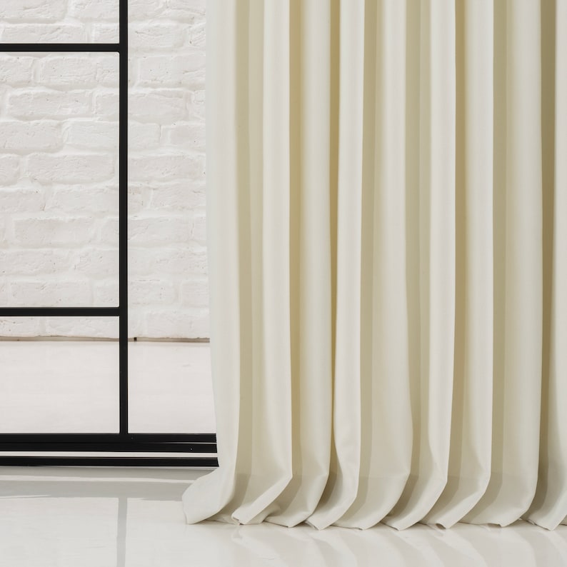 May include: Close-up of a white curtain with pleats, showing the texture of the fabric.