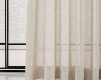 Pode incluir: Uma cortina transparente de cor bege claro com uma textura sutilmente texturizada. A cortina está pendurada na frente de uma janela com uma moldura preta.