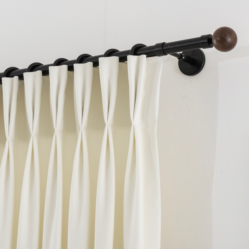 May include: Black curtain rod with wooden finials and white curtains hanging from it.