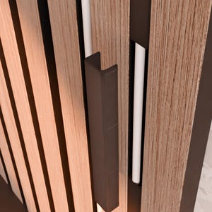 May include: A close-up of a dark brown wooden door with a black metal handle. The handle is a simple, rectangular shape with a slight curve at the top.