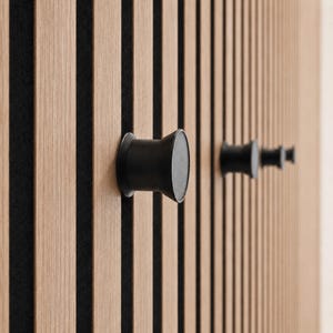 May include: A wall panel featuring vertical light brown wood slats separated by thin black felt strips. Three matte black cylindrical hooks with flared ends are mounted onto the wooden slats, extending outward from the surface of the panel.