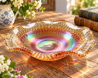 May include: A round glass bowl featuring an iridescent finish with shifting hues of gold, orange, and teal. The bowl has a textured diamond pattern on the interior and a wide, ruffled, scalloped edge that curves outward from the center.
