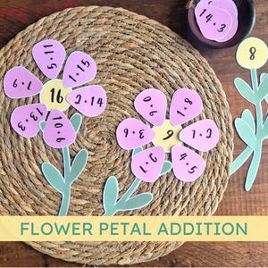 May include: A flower petal addition activity with two pink flowers with numbers on each petal. The flowers are on a woven straw mat. There are two yellow flowers with numbers on them and a small bowl with pink circles with numbers on them.