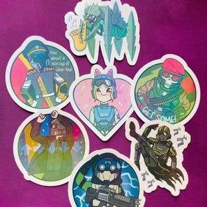 May include: A collection of colorful, die-cut stickers featuring cartoon characters in various poses. Some stickers include text like "How about a nice cup of Liber-tea!" and "Sweet Liberty!" The stickers have a white border and are on a purple background.