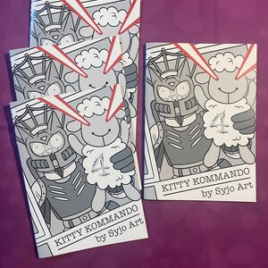 K&ouml;nnte beinhalten: Mehrere Comic-Hefte mit einer schwarz-wei&szlig;en Illustration eines schaf&auml;hnlichen Charakters, der die Zahl 4 h&auml;lt. Der Comic-Titel lautet "KITTY KOMMANDO" von Syjo Art. Rote Laserstrahlen gehen von der Oberseite des Comics aus.